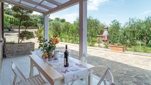 A covered outdoor dining area with a table set for two, surrounded by stone flooring, and overlooking a vineyard. - Lovely apartment in Laureana Cilento (SA) with WiFi (Laureana Cilento (SA))