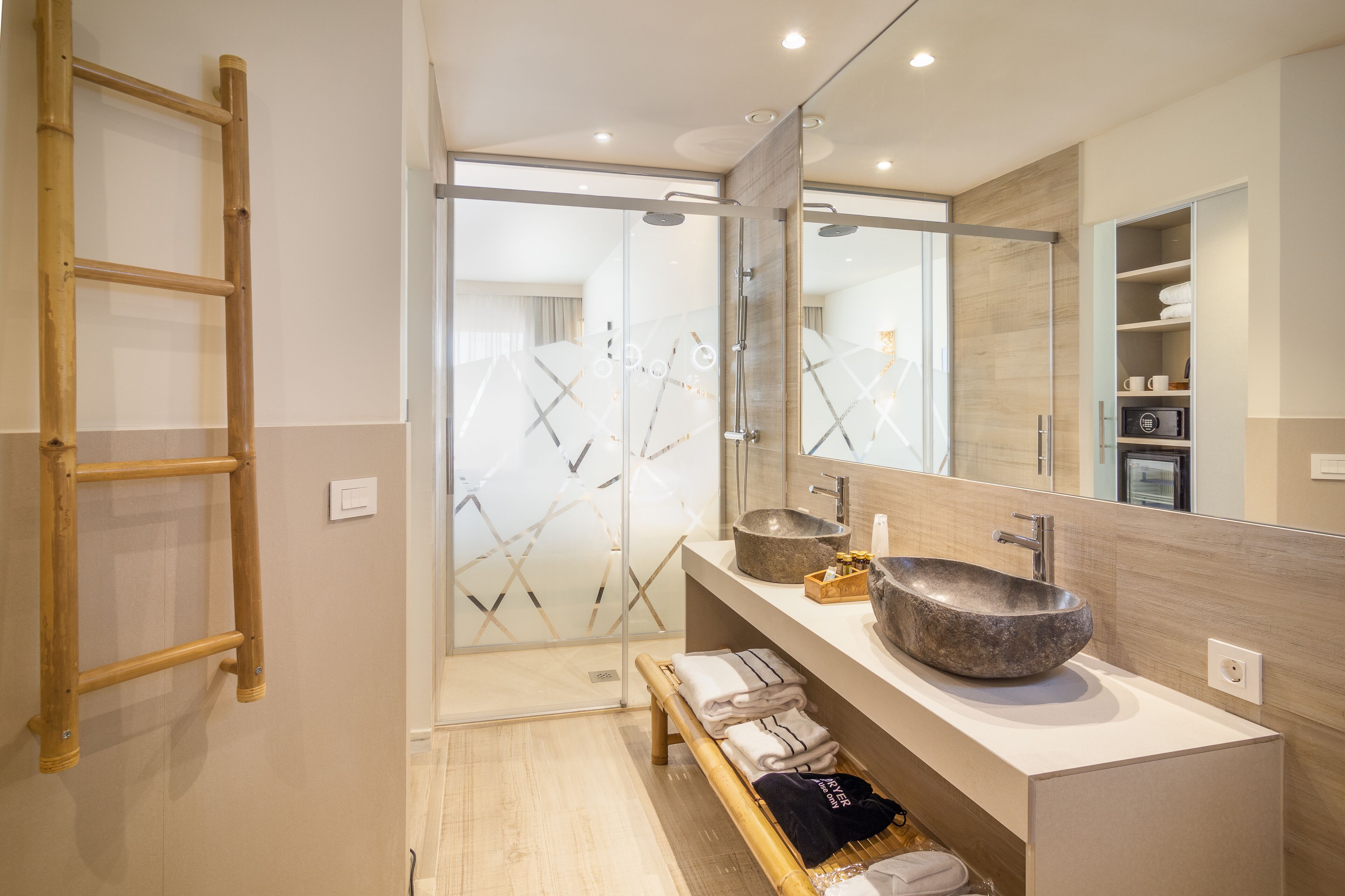 A modern bathroom with a large mirror, two sinks, a wooden ladder, and a towel rack.