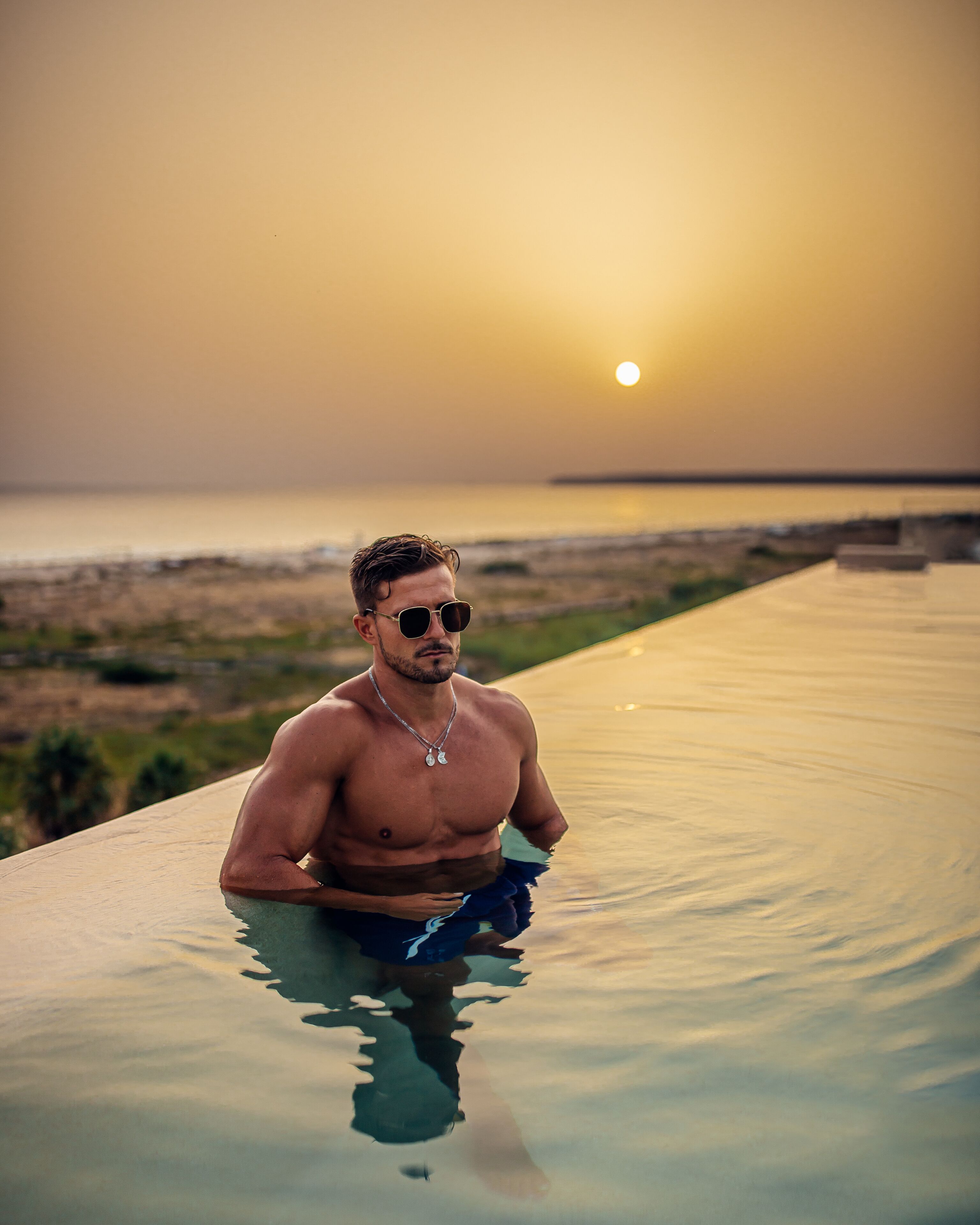 Un hombre en una piscina al atardecer.