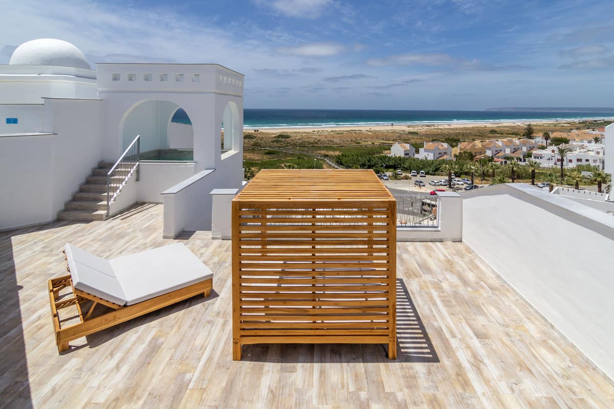 A wooden deck with a lounge chair and a wooden slatted structure.