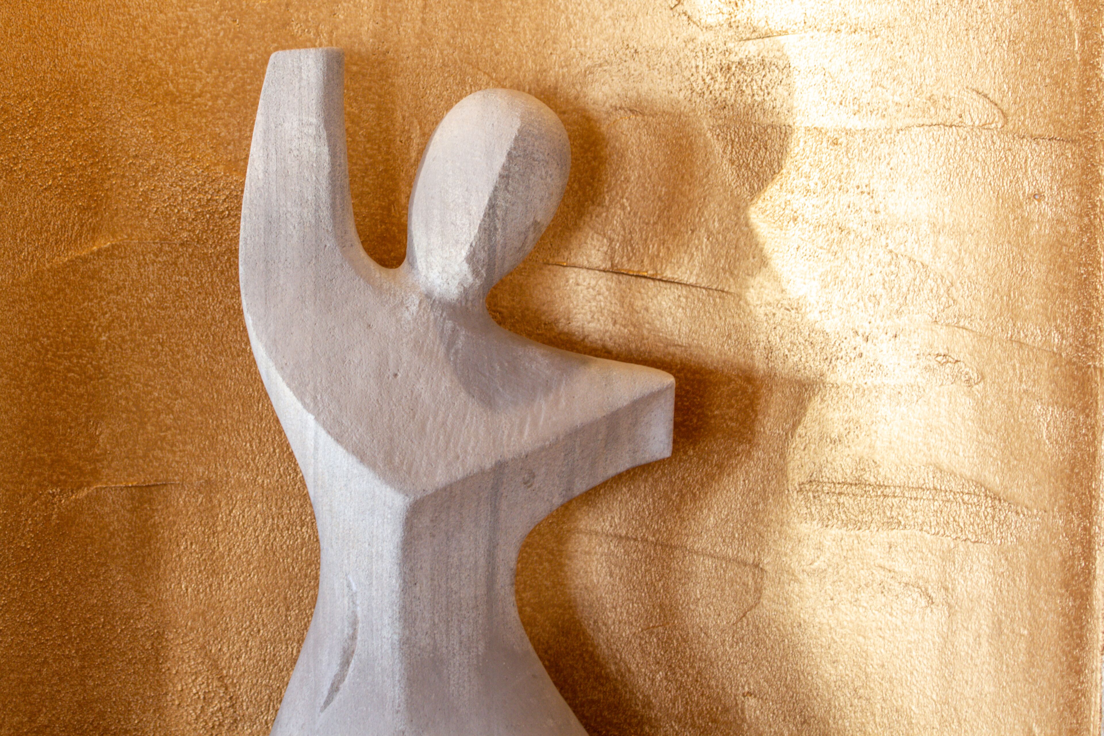A sculpture of a human figure on a textured surface.