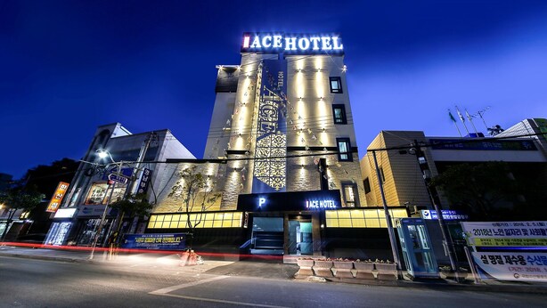 Un hotel con un letrero destacado que dice "ACE HOTEL" y una entrada de estacionamiento señalizada con una 'P'.