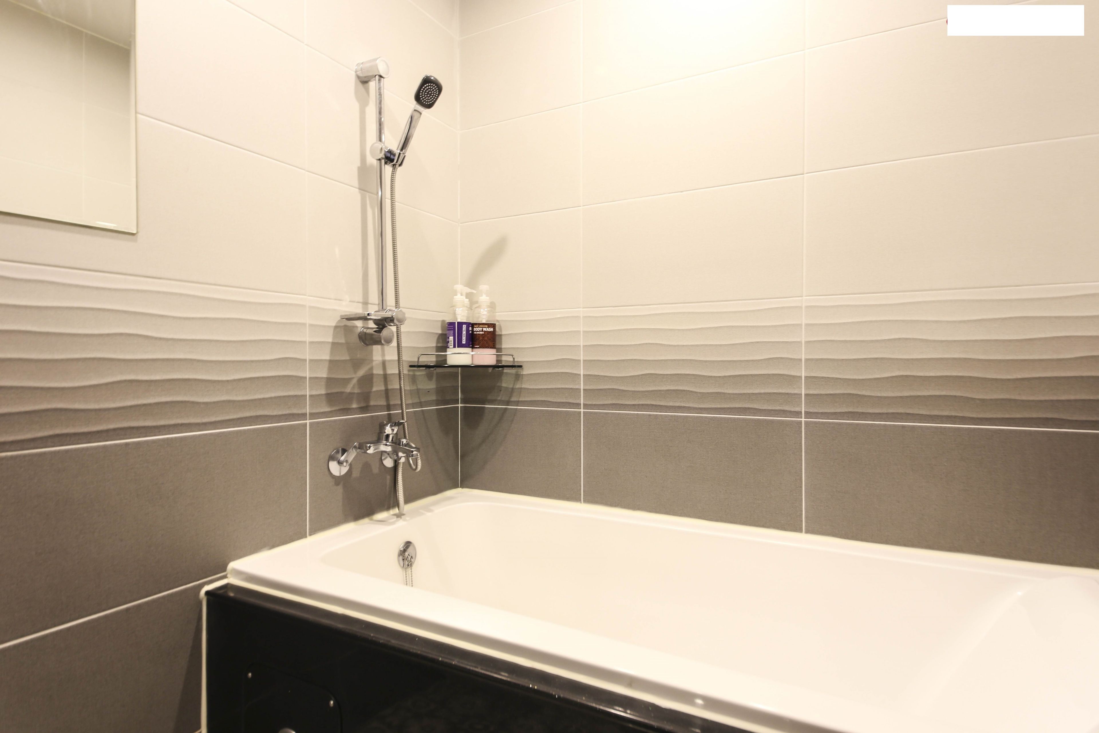 Une salle de bain moderne équipée d’une baignoire, d’une douche et d’une étagère pour les articles de toilette.