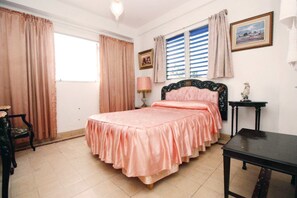Ein Schlafzimmer mit Bett, Stuhl, Tisch und einem fensterbepflegten Fenster.