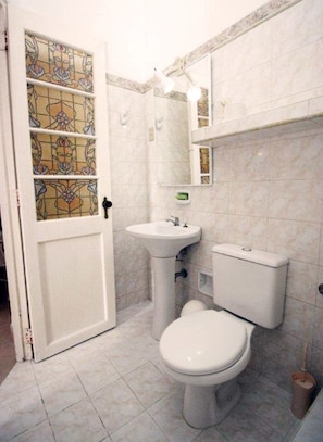 Ein Badezimmer mit Toilette, Waschbecken und einer dekorativen Glasörtür.