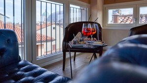 A dining area with a table set for two, a view of rooftops through large windows, and a wooden ceiling. - Locanda delle Mercanzie (Brescia)