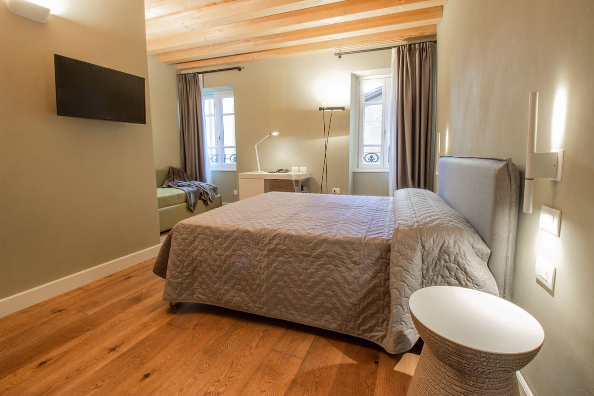 A bedroom with a bed, a bedside table, a lamp, and a TV mounted on the wall.