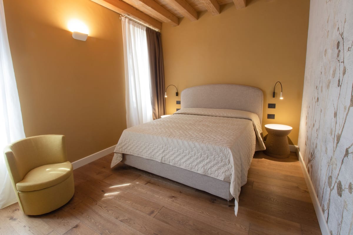A bedroom with a bed, a chair, and a small round table.