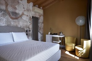 A bedroom with a bed, a desk, a chair, and a wall with a floral pattern. - Locanda delle Mercanzie (Brescia)
