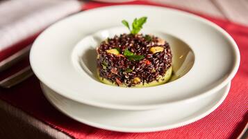 A white plate with a food dish on a red tablecloth.