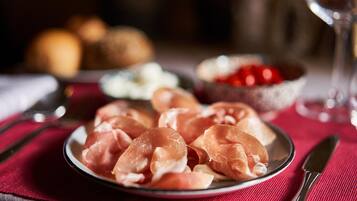 A plate of prosciutto on a table with a red cloth.