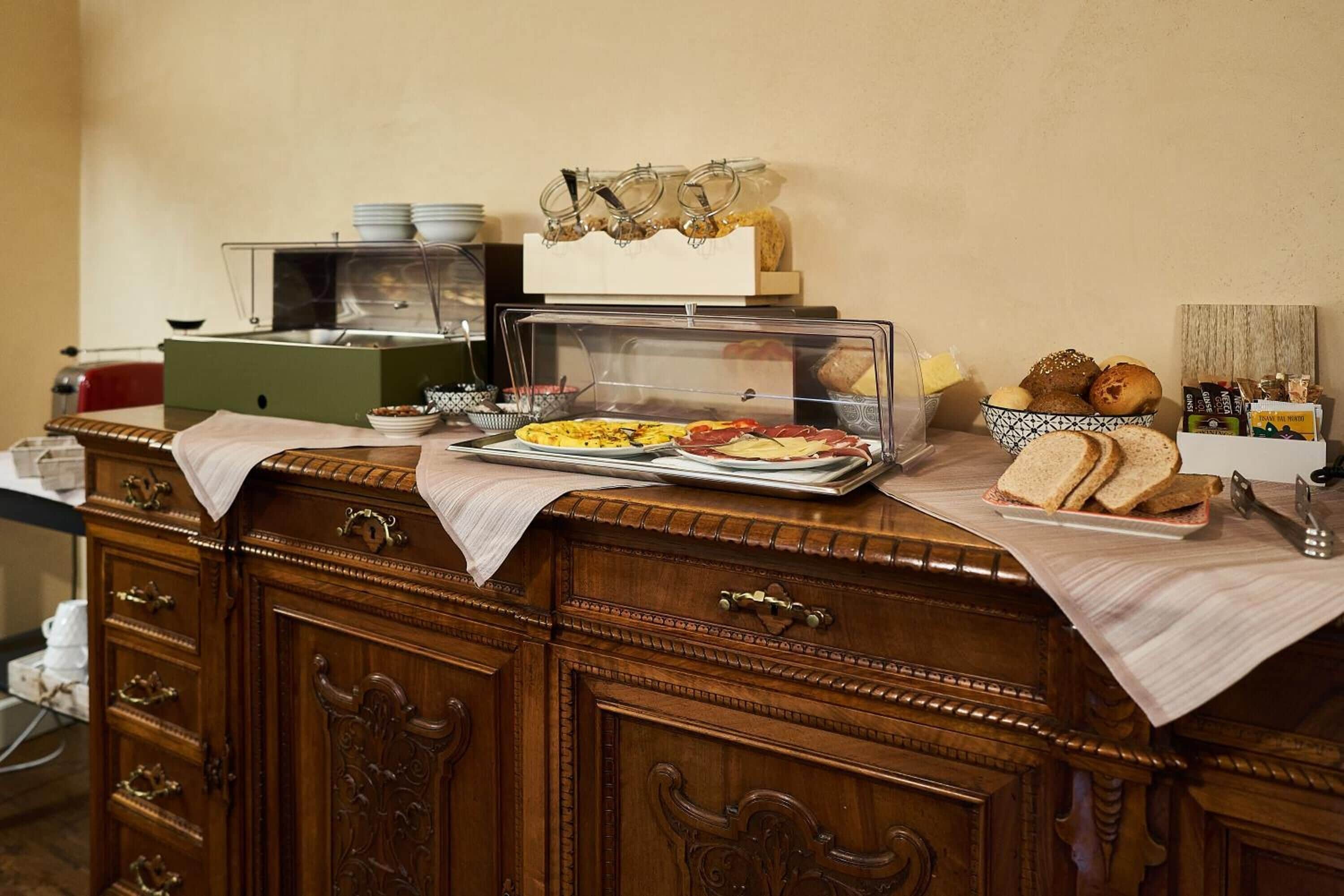 Uma mesa de buffet com diversos alimentos, incluindo pão, doces e um prato quente.