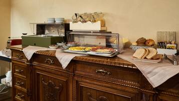 Uma mesa de buffet com diversos alimentos, incluindo pão, doces e um prato quente.
