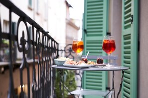 A table with food and drinks on a balcony with green shutters. - Locanda delle Mercanzie (Brescia)