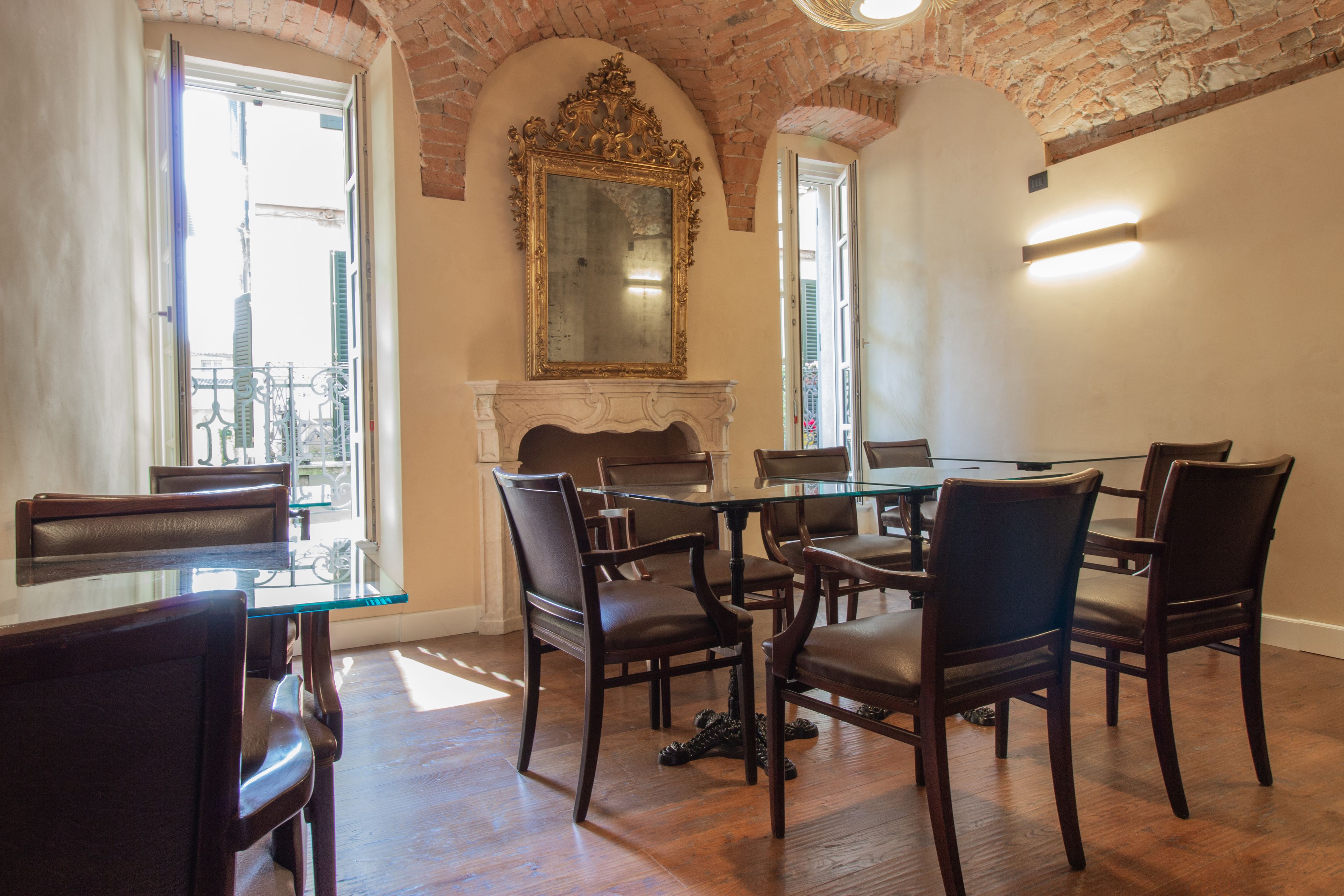 Uma sala de jantar com mesa de vidro e cadeiras de madeira, lareira e um espelho grande na parede.