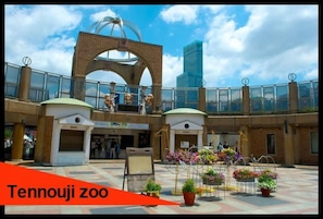 A zoo with a large open plaza, a central archway, and potted plants. - Shinsaibashi Beach House (Osaka)