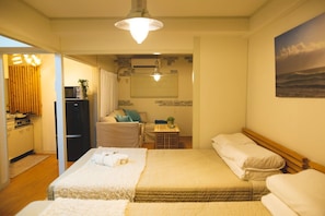 A hotel room with a bed, a desk, a microwave, and a window with blinds. - Shinsaibashi Beach House (Osaka)