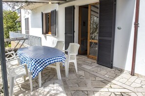 A patio with a table and chairs, a covered seating area, and a door with shutters. - N203 - Numana, large three-room apartment with porch (Numana)