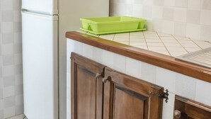 A kitchen with a white refrigerator, wooden cabinets, and a green plastic container on the countertop. - N203 - Numana, large three-room apartment with porch (Numana)