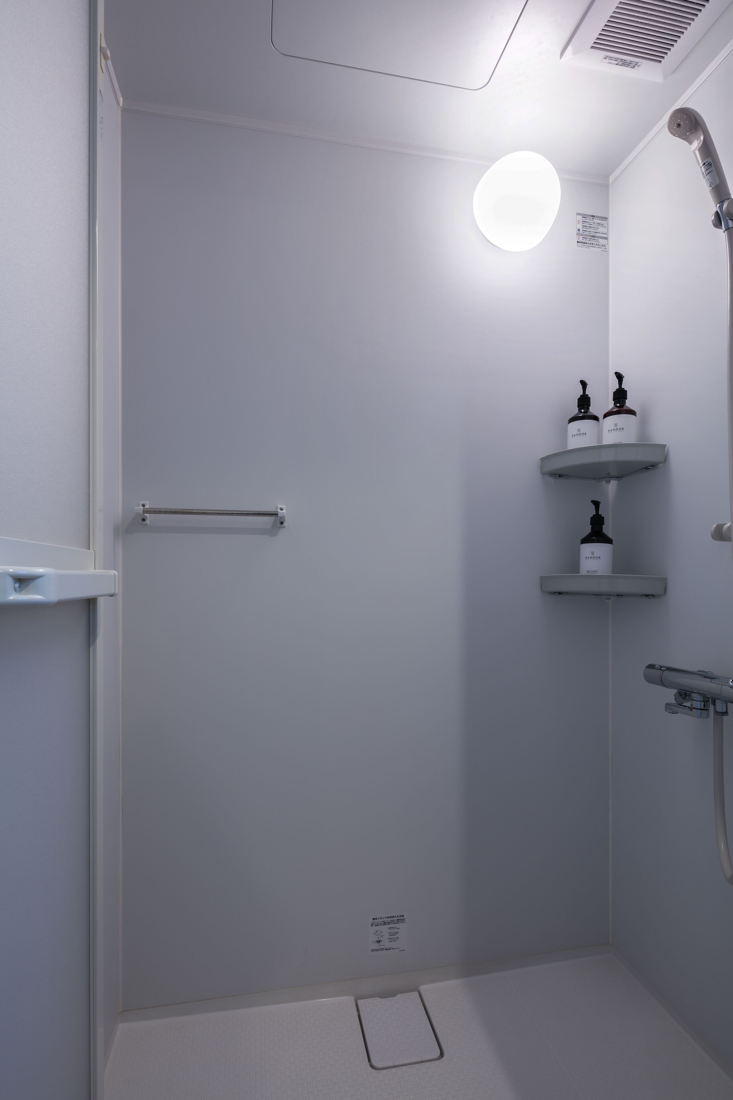 A modern shower with a handheld showerhead, a built-in shelf with toiletries, and a towel rack.