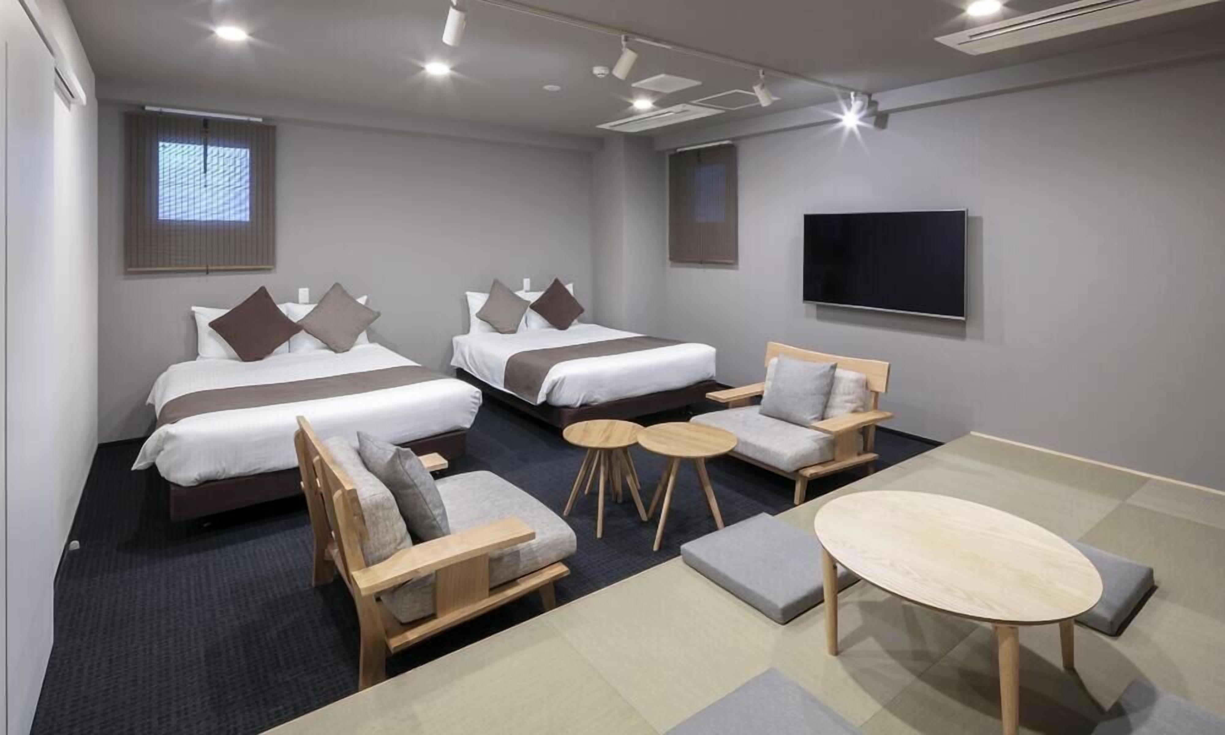 Hotelkamer met twee bedden, een televisie, bureau en zithoek met een ronde tafel en stoelen.