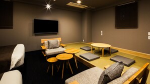 A modern room with a flat-screen TV, a sofa, a chair, a small table, and a round table. - Randor Residence Susukino Suites (Sapporo)
