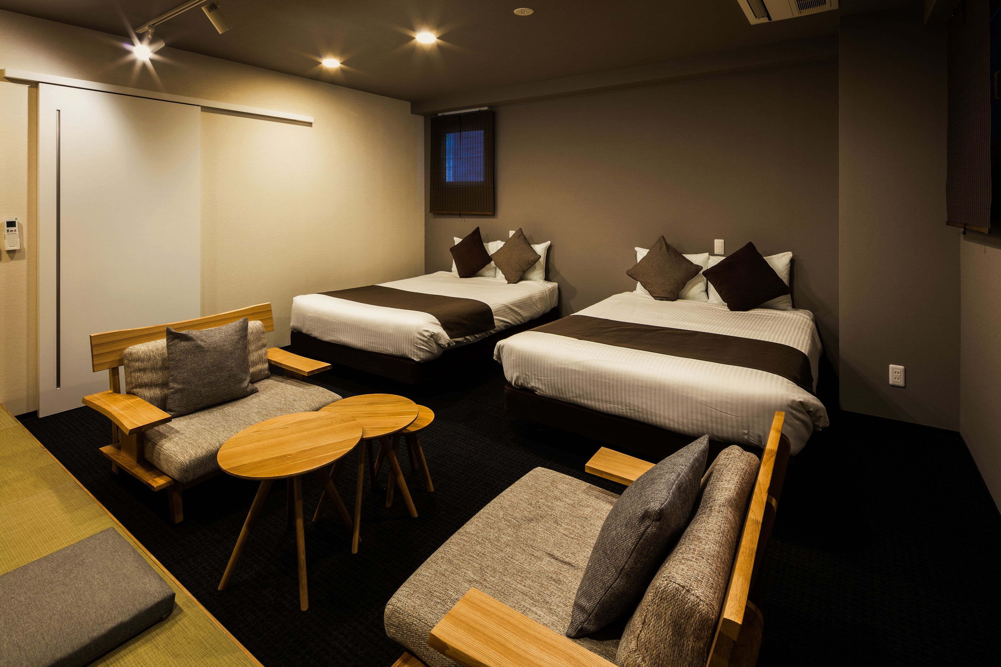 Ein Hotelzimmer mit zwei Einzelbetten, einem Schlafsofa, einem kleinen Tisch und einem Schreibtisch.