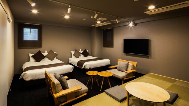 A hotel room with two beds, a sofa, a small round table, and a TV mounted on the wall. - Randor Residence Susukino Suites (Sapporo)