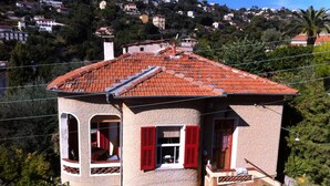 A two-story house with a red-tiled roof, a balcony, and a garden area. - Villa Bennecourt (Nice)