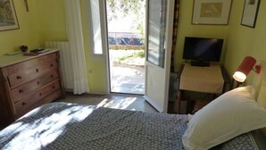 A bedroom with a bed, a dresser, a television, and a window with a view of the outside. - Villa Bennecourt (Nice)
