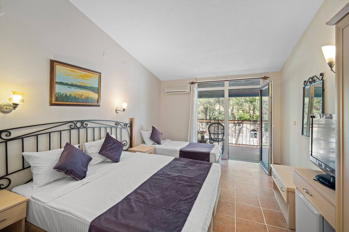 Une chambre d’hôtel avec deux lits, un balcon, un tableau et une télévision.
