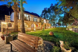 Un edificio de piedra con un banco de madera y un jardín bien cuidado.