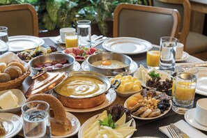 Un bufé de desayuno con diversas opciones de comida, incluyendo pan, queso y frutas.