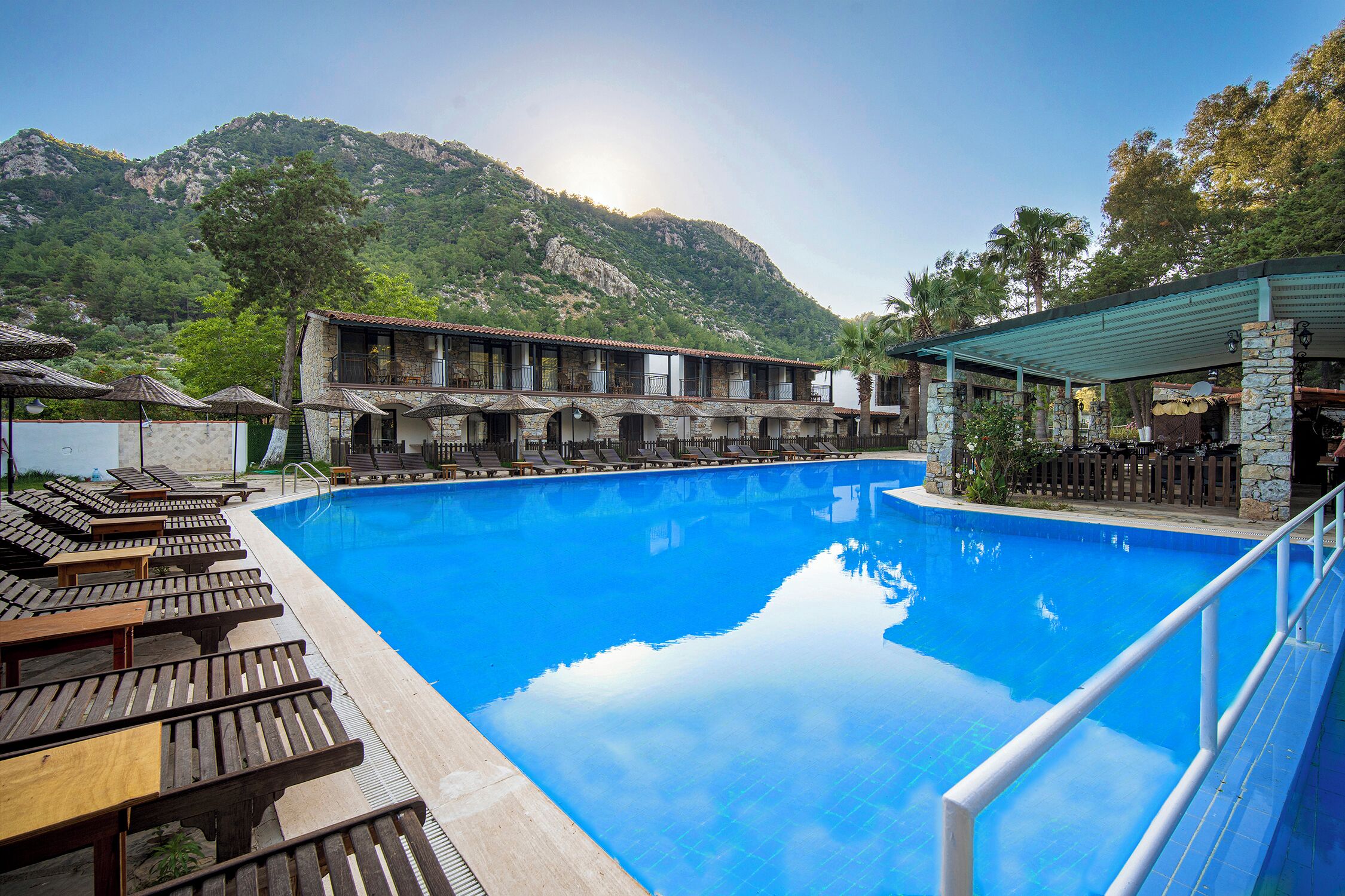 Uma área de piscina com espreguiçadeiras e um edifício com varandas.