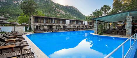 Uma área de piscina com espreguiçadeiras e um edifício com varandas.