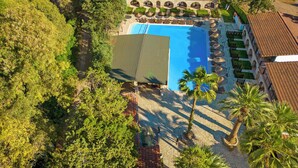 An aerial view of a resort with a swimming pool, palm trees, and a building with a tiled roof. - Alados Otel (Marmaris)