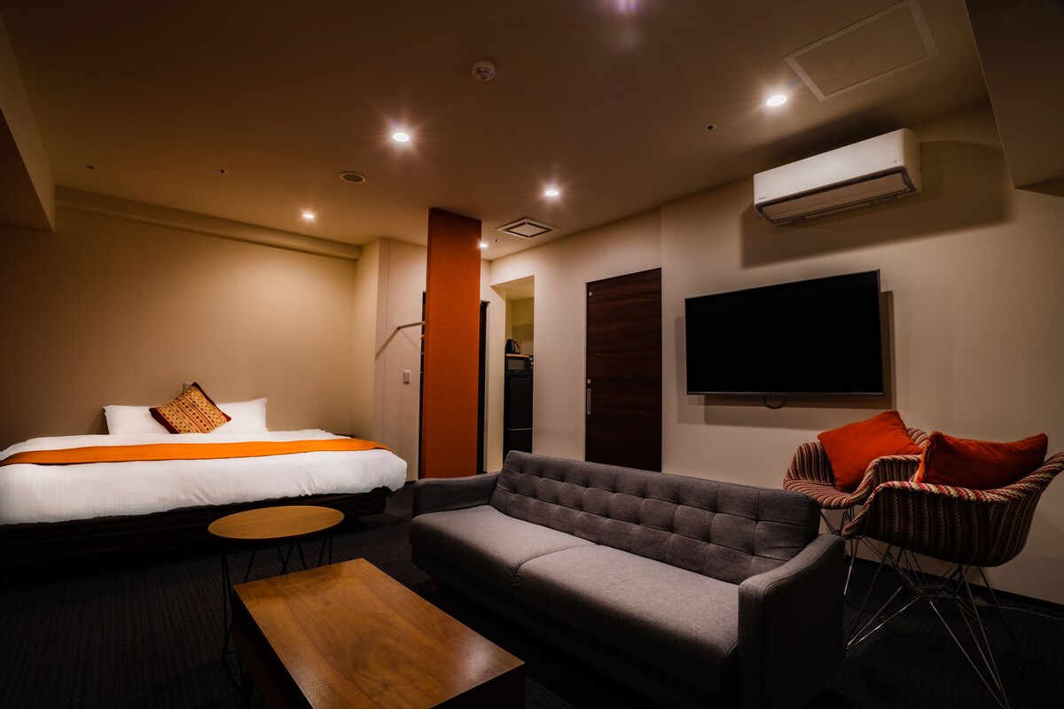 Ein Hotelzimmer mit Bett, Sofa, Sessel, kleinem Tisch und Klimaanlage.