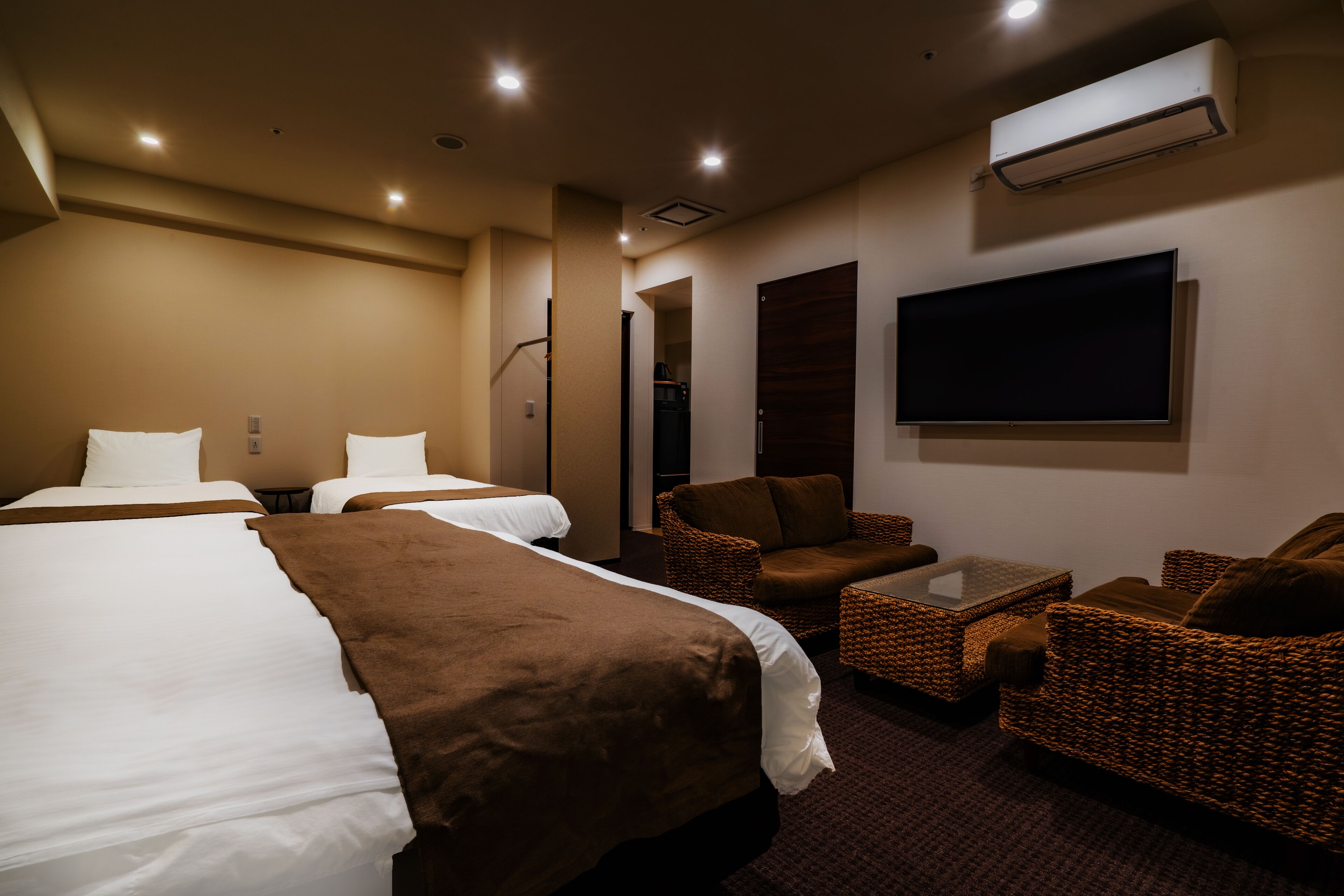 Une chambre d’hôtel avec deux lits, un canapé, une table basse et un téléviseur.