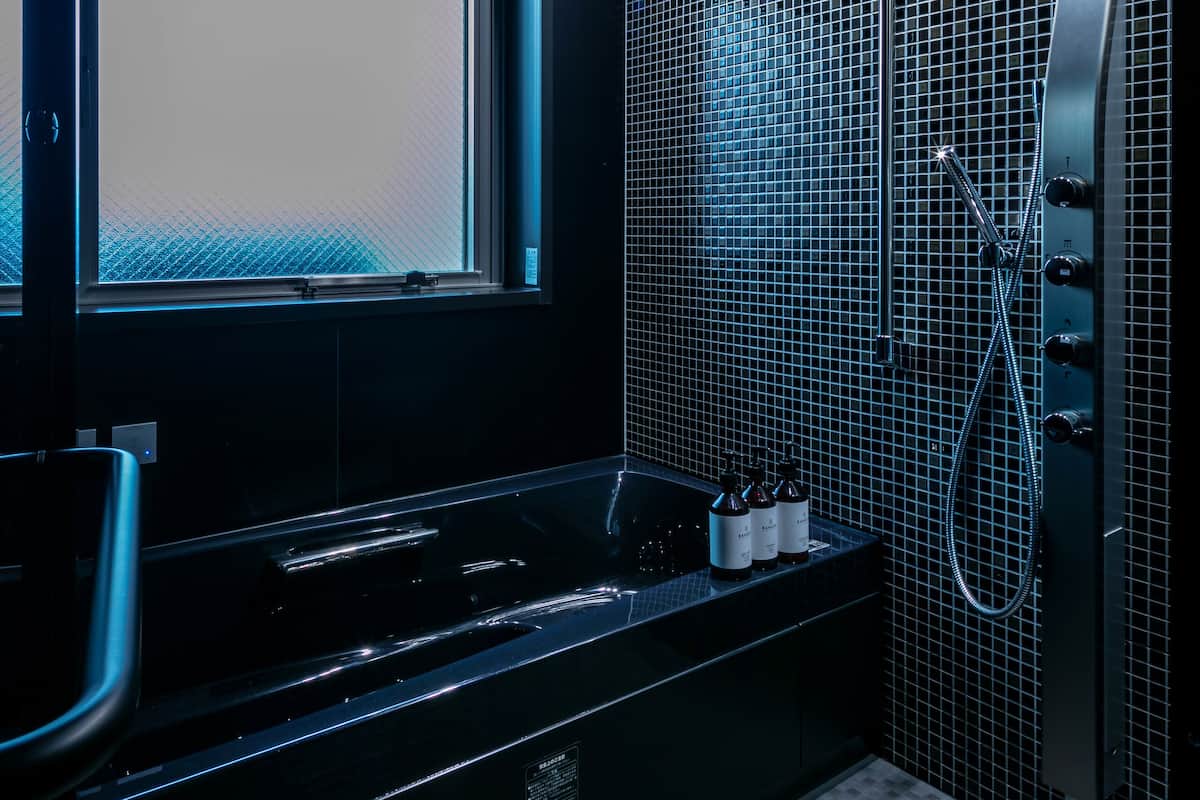 A modern bathroom with a large bathtub, a window, and a shower area.
