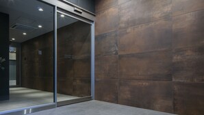 A modern interior with a glass door leading to a room, a wall with a textured finish, and a ceiling with recessed lighting. - Randor Residential Hotel Sapporo Suites (Sapporo)