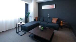 A modern living room with a sectional sofa, a coffee table, and a small side table with a plant. - Randor Residential Hotel Sapporo Suites (Sapporo)