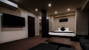 A modern hotel room with a large bed, a flat-screen TV, a sofa, and a small table. - Randor Residential Hotel Sapporo Suites (Sapporo)