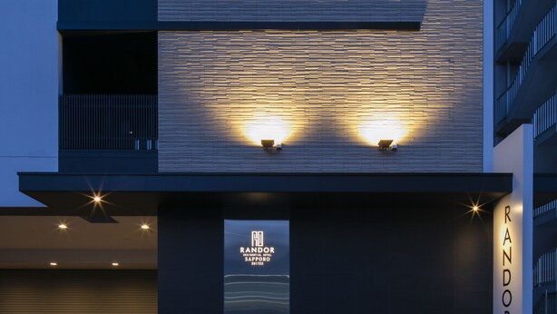 A modern building with horizontal wooden panels, a visible entrance, and the name "RANDOR" on the facade. - Randor Residential Hotel Sapporo Suites (Sapporo)