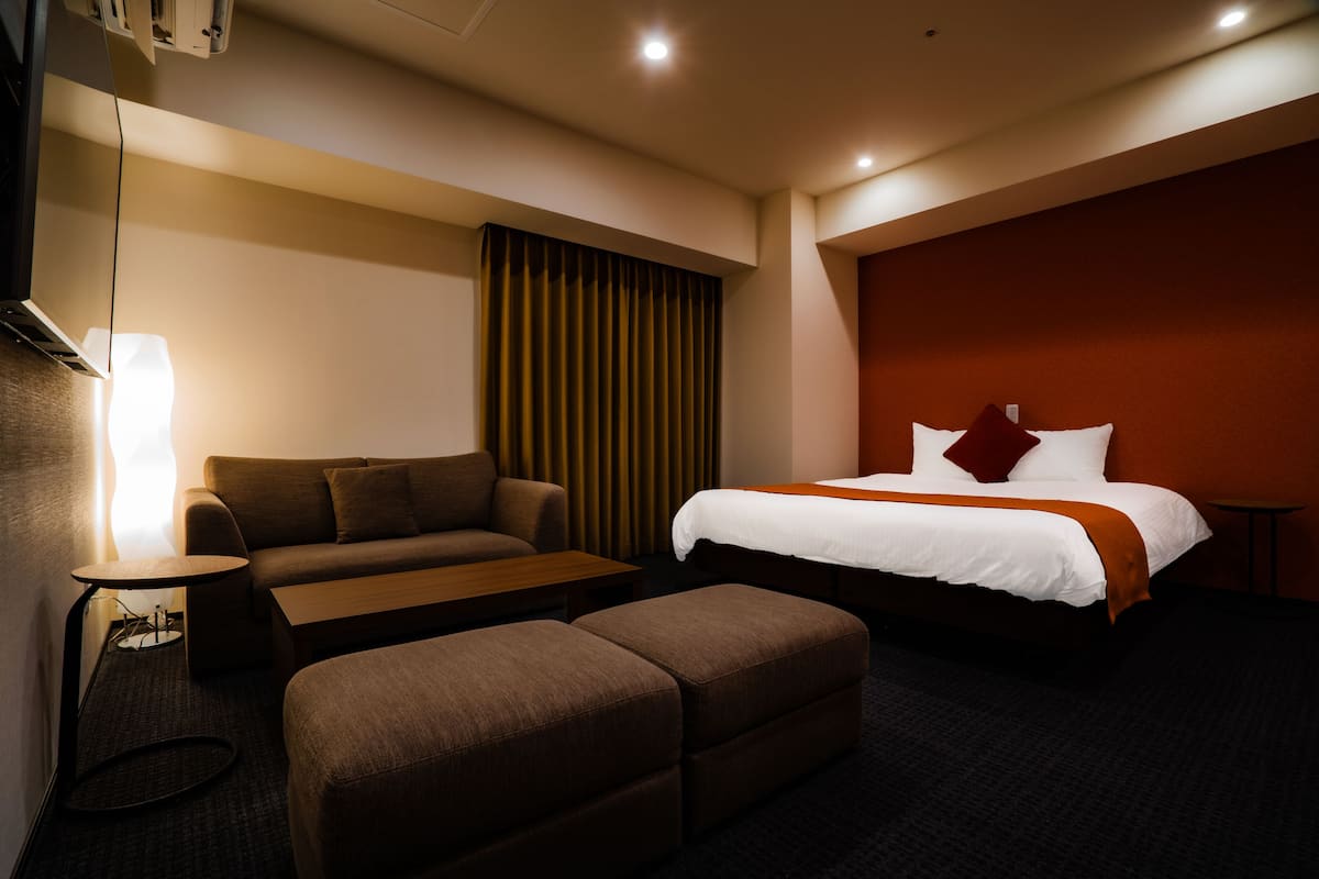 A hotel room with a bed, a sofa, a small table, and a bench.