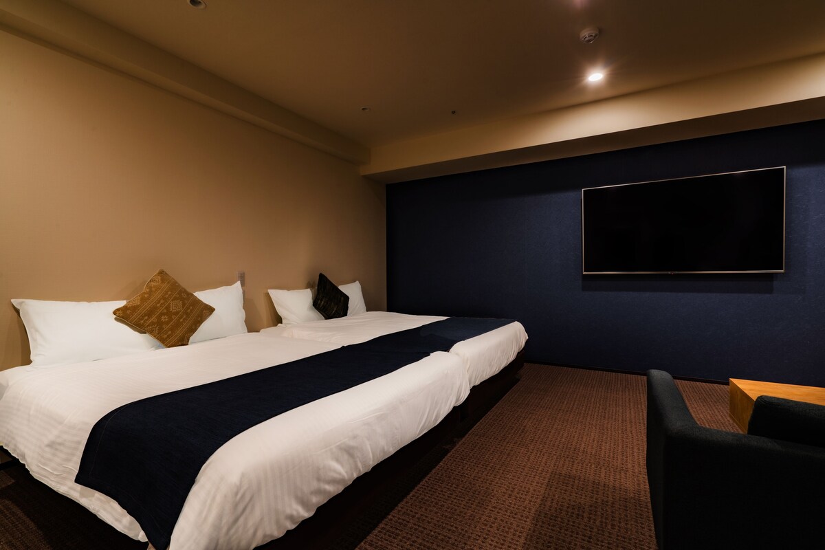 Ein Hotelzimmer mit einem großen Bett, einem an der Wand befestigten Flachbildfernseher und einer Sitzecke mit einem kleinen Tisch und Stühlen.