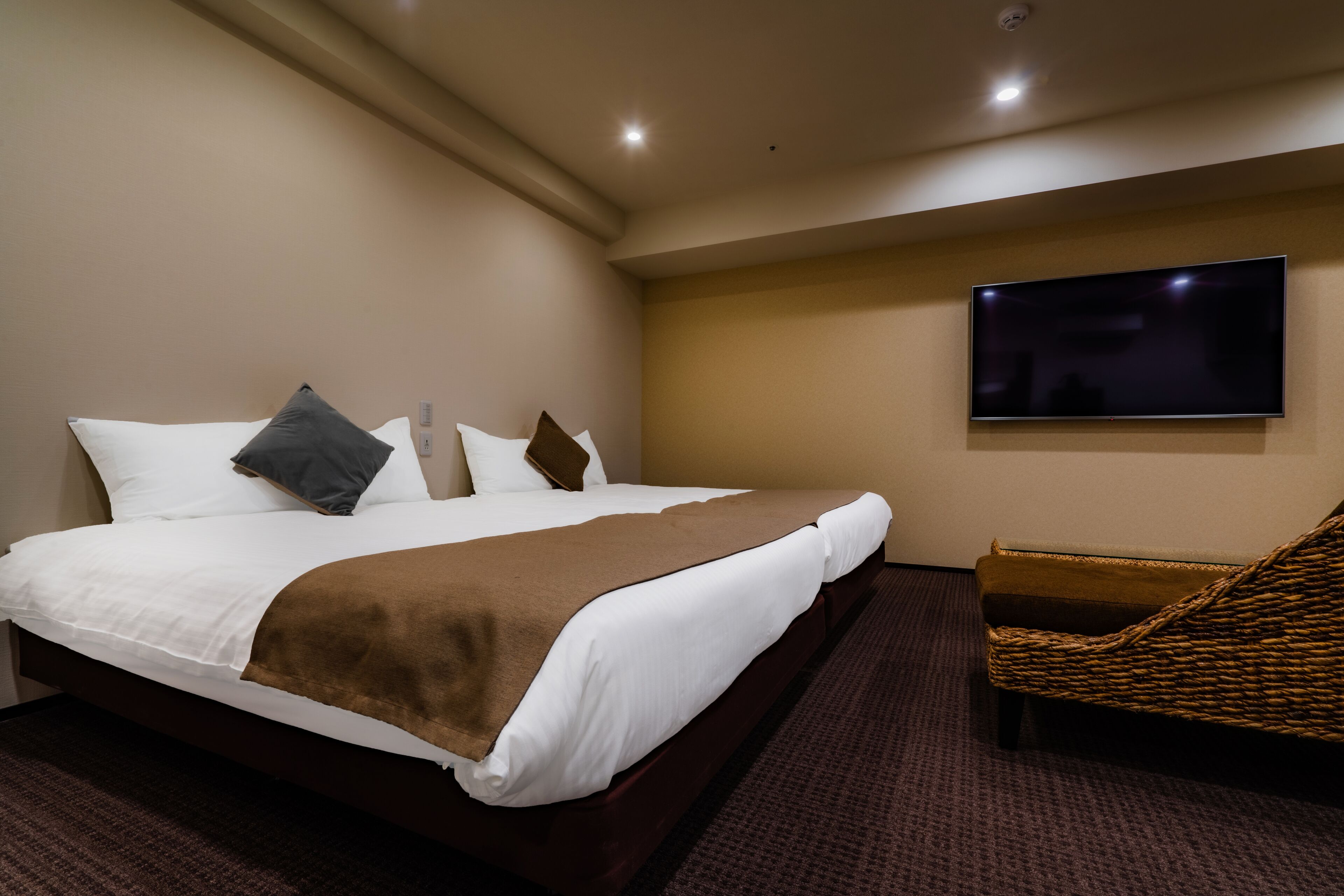 Ein Hotelzimmer mit einem großen Bett, einem flachbildfernseher an der Wand und einem Korbsessel.