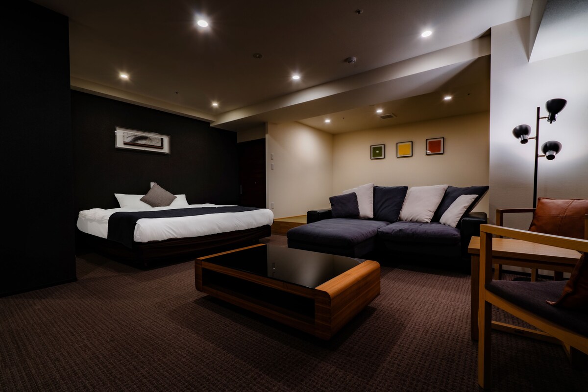Ein modernes Hotelzimmer mit Bett, Sofa und einem kleinen Holztisch.