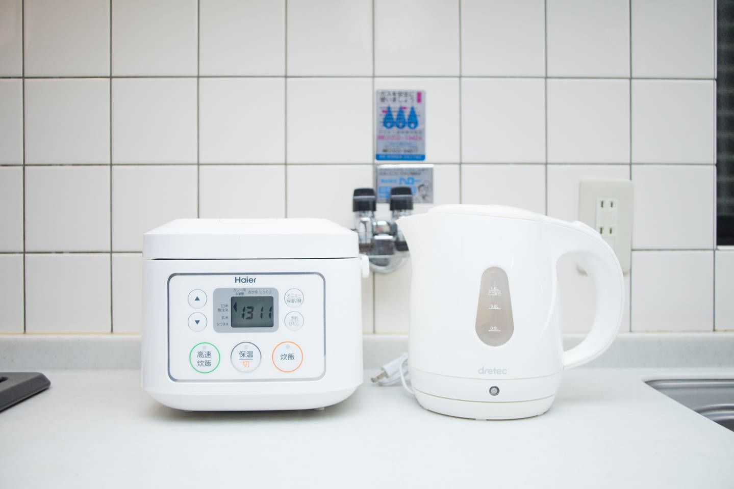A kitchen with a rice cooker and a kettle on the counter.