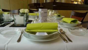Een gedekte tafel voor diner, met een menukaart, helder glaswerk en netjes gevouwen groene servetten.