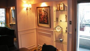 A hotel lobby with a seating area, a wall-mounted lamp, a framed artwork, and a glass display case with decorative items. - My home in Buenos Aires | 1937 sqft | 2 bdr | n/STelmo (Barracas)